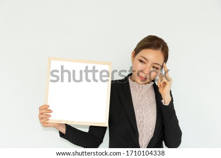 Beautiful woman wear work clothes. She is a successful businesswoman. She is holding a white board and have white  background.