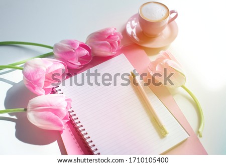 Empty notebook spring pink tulips flowers, cup of coffee. Mockup notepad on pink background. Still life. Spring romantic mood. Colorful light. Feminine desctop. Top view. Copy space