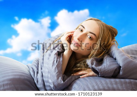 creative image: Girl woman in bed after sleep at the sky background isolated, sleep female, stay at home concept, coronavirus quarantine, wake up in the morning