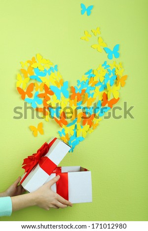 Paper butterflies fly out of box on green wall background