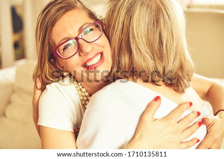 Beautiful senior mom and her adult daughter are hugging and kissing.