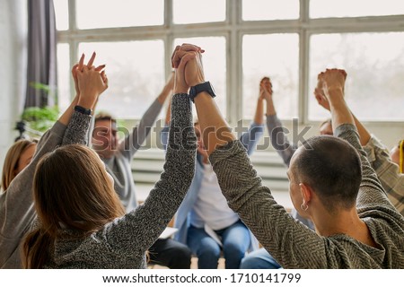 young caucasian people celebrating recovery from alcohol addiction, team work of anonymous addicts club, raised hands up together Royalty-Free Stock Photo #1710141799