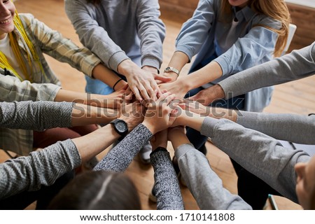 top view on people hands holding together, friendly team work at meeting. club of anonymous alcoholics