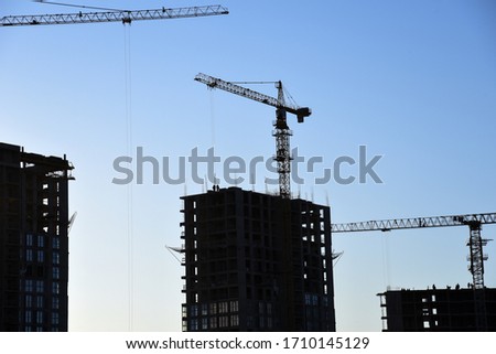 Tower crane lifting concrete bucket for pouring concrete during construction residential building on blue sky background. Builder workers during formwork and pouring concrete. New skyscraper