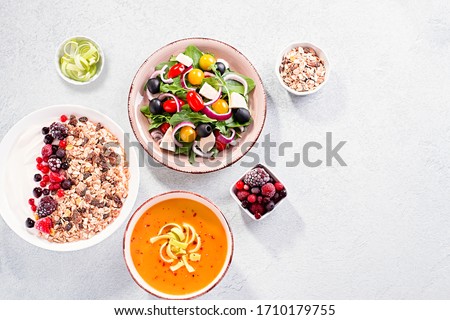 Carrot cream soup, Greek salad, granola bowl with yogurt on concrete table top with copy space. Assortment of dishes for diet, suitable for volumetrics diet and other nutrition strategies, top view Royalty-Free Stock Photo #1710179755