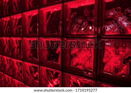 Glass blocks with color illumination. Textured glass bricks in the dark. Red color, close up.