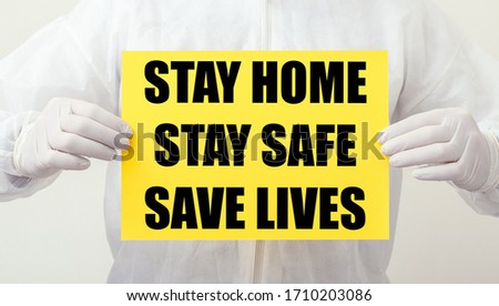 Stay Home Stay Safe Save Lives text on yellow warning sign in doctors hands. Coronavirus, Covid-19 self quarantine isolation. Medical, healthcare social distancing concept.