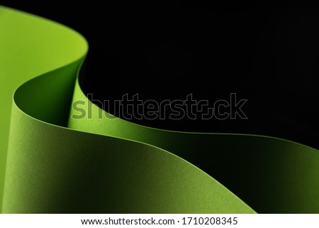Abstract - two sheets of rolled green paper on black background. Simple, isolated object with copy space perfect for illustrating various concepts and ideas. Selective focus (shallow DOF).