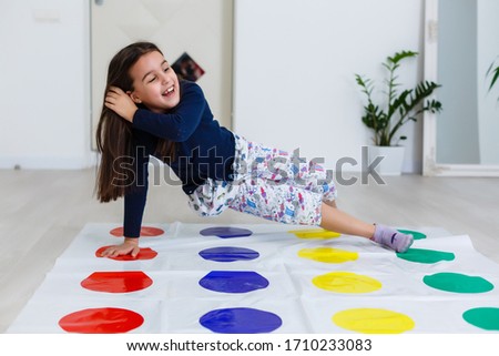 little girl playing on a twister game at home. Girl smiles and looks up Royalty-Free Stock Photo #1710233083
