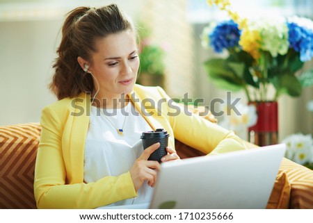 elegant student in jeans and yellow jacket at modern home in sunny day using web school on a laptop.