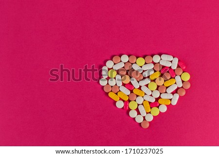 Many different pills and tablets folded in shape of heart on pink background. Many pills and tablets with space for text. Health care. Top view. Copy space. New image. Pharmaceutical picture