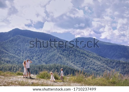 A boy and a girl run to their parents on the mountain. The family travels on a sunny summer day.