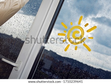 The sun painted on a wet window in cloudy weather