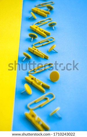 Office supplies in the form of colored buttons and paper clips, clothepins on yellow and blue background, copy space, border and frame, back to school concept of office chancery