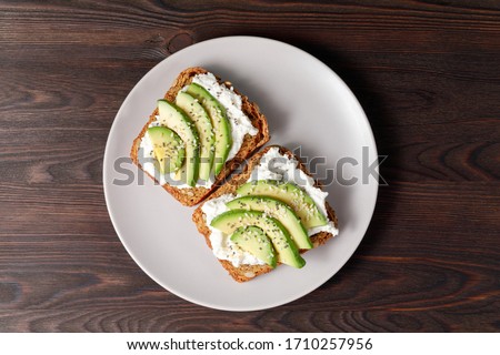 Variation of healthy toasts with avocado cream cheese and whole wheat rye bread on a plate. Delicious snacks and avocado sandwiches. Food composition, tasty Italian meal. Top view. Royalty-Free Stock Photo #1710257956
