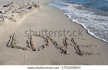 The inscription love in the sand on the coast of the Baltic Sea in summer