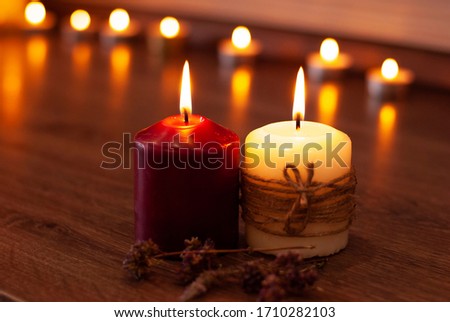 Aromatherapy flame closeup picture. Beautyful burning light yellow creme vanilla candles and wine dark red with wooden background. Evening spa lightens