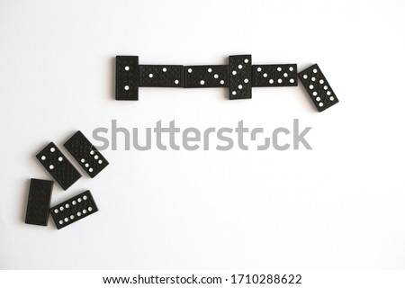 Black dominoes lie in line on white background, top view. Board game. Place for text