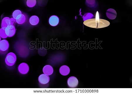 The concept of prayer and hope.The concept of prayer and hope.Flame of a burning candle at night with abstract round bokeh purple background of Christmas lights. Royalty-Free Stock Photo #1710300898