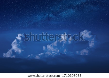 Rainy clouds in a moonlight under the milky way in a starry sky at night.