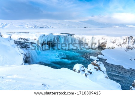 Half frozen Icelandic river Skjalfandafljot flowing over the waterfall Godafoss in Winter. Still flowing strongly but snow covered and with large icicles Royalty-Free Stock Photo #1710309415