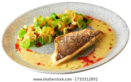 Tasty grilled sea bass fillet served with steamed brussel sprouts, roasted mushrooms, potato, caramelized onion and creamy sauce. Isolated over white background.