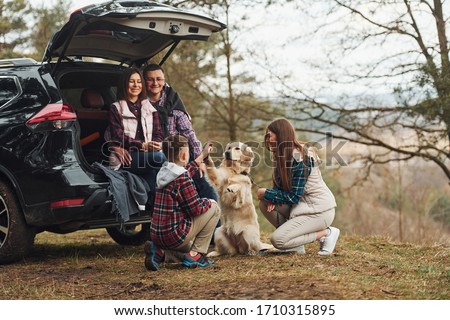 Happy family have fun with their dog near modern car outdoors in forest. Royalty-Free Stock Photo #1710315895