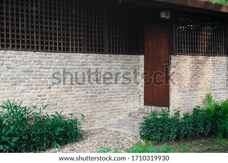 Brown painted vintage wooden door set into left side of old brick wall