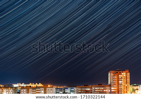 Long exposure image showing star trails over the city. The time-lapse in the night during self-isolation, pandemic