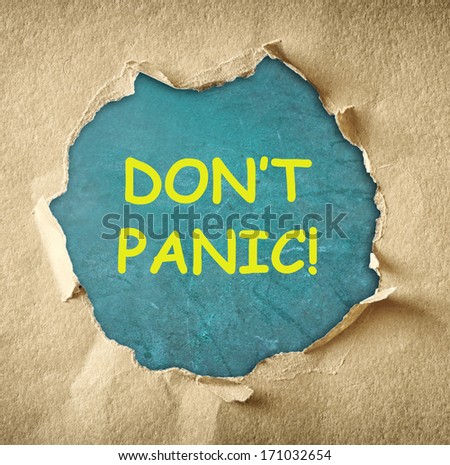 the phrase dont panic written over blue chalkboard through hole in torn paper