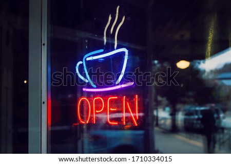 Neon open sign with coffee cup  shot through dirty glass door,  shallow focus on neon cup