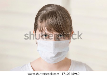 Girl in a medical mask looks at the camera with a tense look