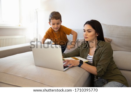 Cute little boy and charming woman using laptop at home stock photo