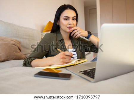 Attractive lady making notes while listening online education course stock photo