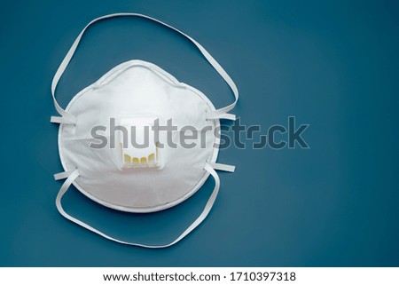White face medical mask against virus, flu and coronavirus isolated on dark blue background. Protective respirator with valve. Royalty-Free Stock Photo #1710397318