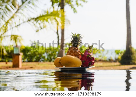 Plate of exotic fruits near swimming pool