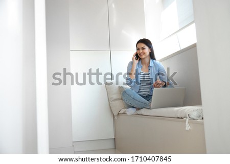 Happy woman is sitting on window still and using both smartphone and notebook stock photo. Website banner
