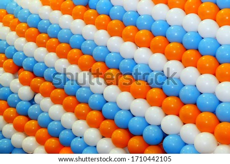 Garlands of balloons in orange, blue and white color as a background. Multi-colored balloons tied in rows for decoration