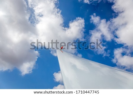 blue glider wing pointing towards blue sky with clouds