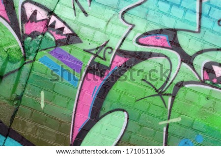 Abstract colorful fragment of graffiti paintings on old brick wall in green colors. Street art composition with parts of unwritten letters and multicolored stains. Subcultural background