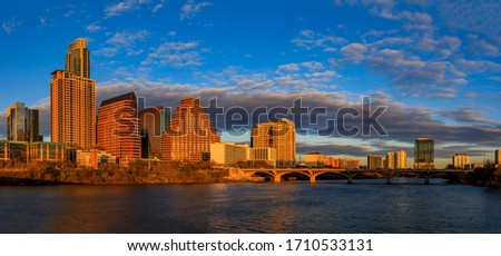 Panorama with downtown high-rises reflecting sunset golden hour light viewed across Lady Bird Lake or Town Lake on Colorado River in Austin, Texas USA Royalty-Free Stock Photo #1710533131