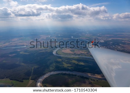 glider wing, blue sky with clouds, river and forest
