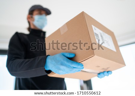 Home delivery shopping box man wearing gloves and protective mask delivering packages at door. Royalty-Free Stock Photo #1710550612