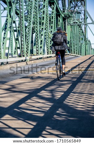 A Slender girl on a bike pedals a bicycle on the Hawthorne drawbridge preferring an active healthy lifestyle using cycling ride and cycle as an alternative environmentally friendly transportation