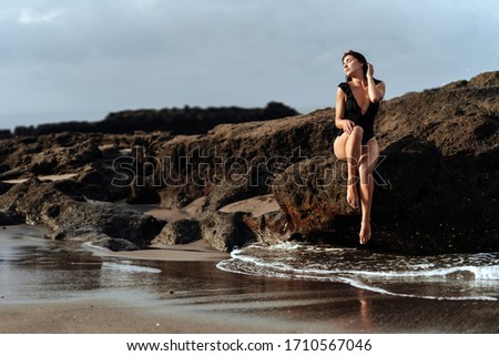 Portrait of pretty beautiful sport fashion woman in black bikini posing in summer near the ocean on tropic island on vacation