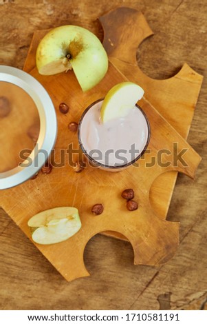 Yogurt with apple and nuts on a wooden background. Daylight.
