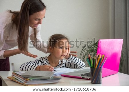 Furious adult woman screaming at daughter while she helping to do her homework assignment at home