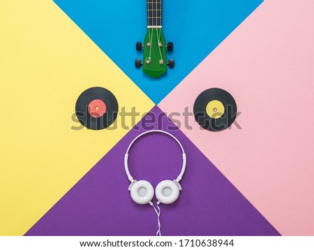 Headphones, guitar and vinyl discs on an abstract background. Retro technique for playing music.