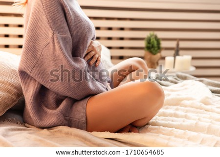 Beautiful pregnancy indoors. Happy pregnant woman hugs tummy at home