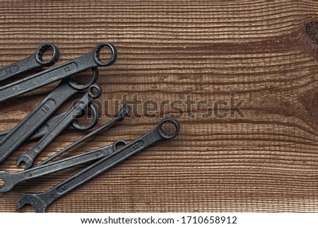 black steel wrench different sizes tool set layout on dark brown wood textured background with copy space